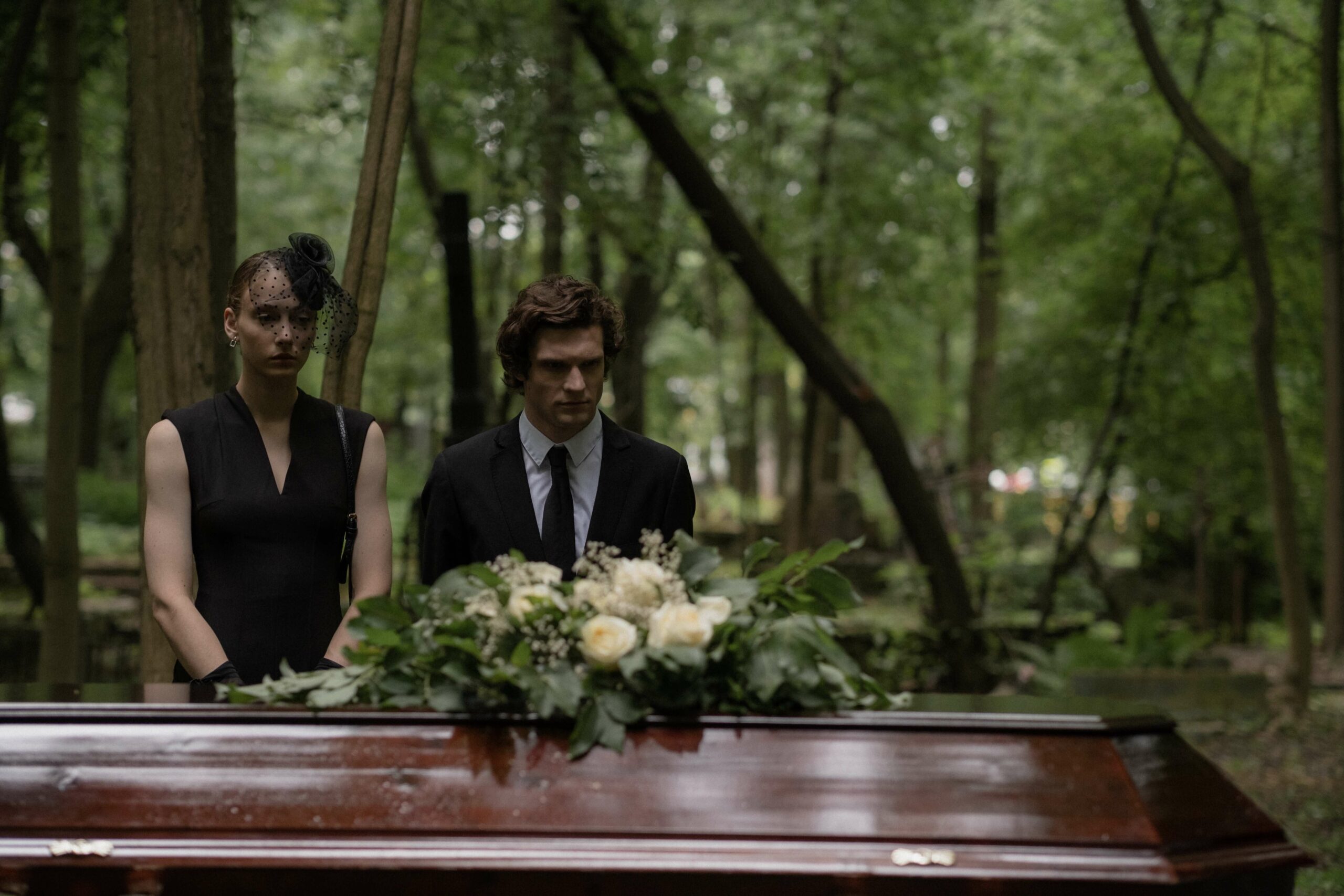 people standing at a casket mourning